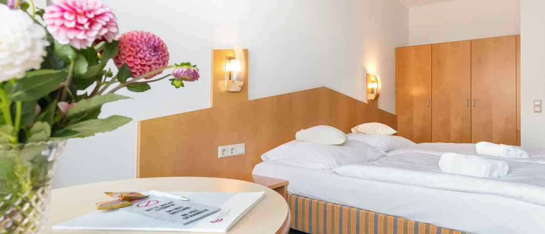 Gästezimmer mit Doppelbett und Blumenstrauß